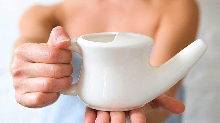 person holding white neti ceramic pot close up view