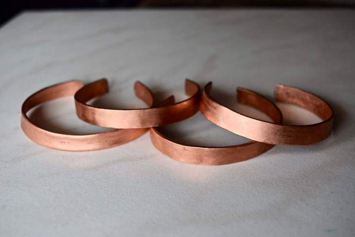 four copper smooth brushed bracelets placed on a table