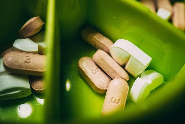 different types of pills placed in a green container selective focus close up