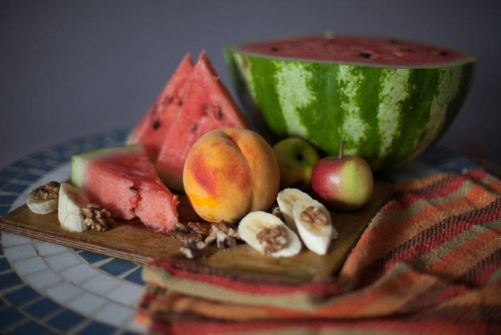 watermelon peach sliced bananas placed on a wooden board